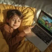 Child watching a laptop while a parent reviews YouTube Kids safety settings